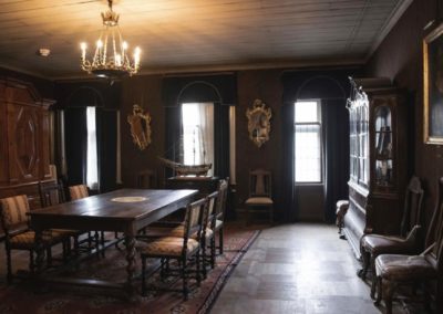 Kungasalen at Gathenhielmska Huset. The room features a wooden table, chairs, cabinets, mirrors and a portrait painting in a glass frame.