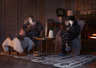Two women sat in armchairs, looking at their phones